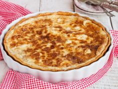 a cheese pie in a white dish on a red and white checkered cloth