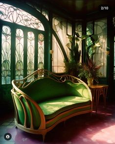 a green couch sitting in front of a window next to a potted plant