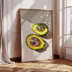 an avocado cut in half sitting on top of a wooden floor next to a window