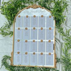 the seating chart is set up in front of some greenery for an outdoor wedding