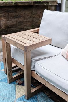 a wooden table sitting on top of a blue rug next to a white couch and pillows