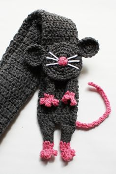 two crocheted mice are laying next to each other on a white surface, one is gray and the other is pink