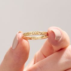 a close up of a person holding a gold ring with leaves on the inside of it