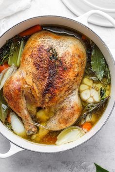 a whole chicken in a pot with vegetables