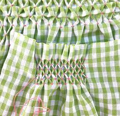 green and white checkered fabric with pink thread on the bottom, along with red stitching