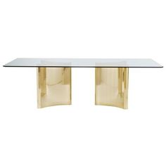 a glass and brass dining table with two curved legs, viewed from the front view