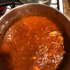 a pot full of red sauce sitting on top of a stove next to an oven