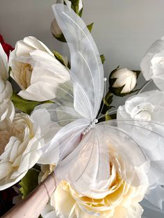 a white flower with a butterfly on it's wing in front of some flowers