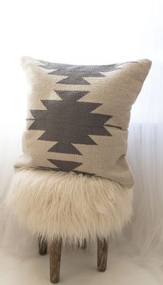 a white and black pillow sitting on top of a wooden stool