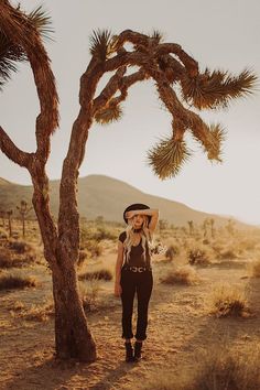 a woman standing next to a tree in the desert