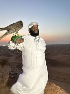 a man with a falcon on his hand in the desert