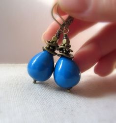 Chubby vintage teardrops in Denim Blue are wrapped by hand in decorative antiqued brass beads and suspended to dangle from matching antiqued brass lever back style ear wires. These lovely vintage beads are opaque and smooth with a shiny. Focal: Vintage opaque Denim Blue teardrops, 3/4'' tall Metal: Antiqued Brass Length: Approximately 2'' tall from the top of the ear wire, lightweight. Made with lead-safe and nickel free brass. These earrings are made to order. Please allow 2-3 business days bef Blue Bohemian Pearl Drop Earrings, Blue Pearl Drop Bohemian Earrings, Blue Teardrop Brass Earrings, Earrings Summer, Brass Beads, Summer Earrings, Vintage Beads, Summer Earring, Earrings Blue