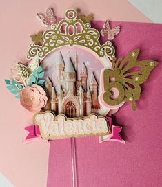 a pink and gold birthday card with a princess castle on it's side, surrounded by butterflies