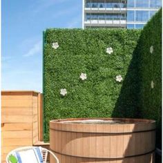 a hot tub sitting on top of a wooden deck next to a tall green wall