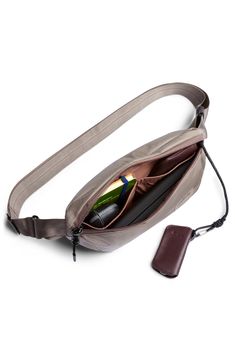 an open purse with a bottle in it and a cell phone attached to the strap