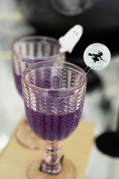 two purple glasses sitting on top of a wooden table