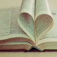 an open book with pages folded into the shape of a heart on top of it