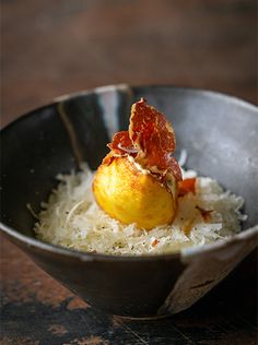 a black bowl filled with food on top of a wooden table