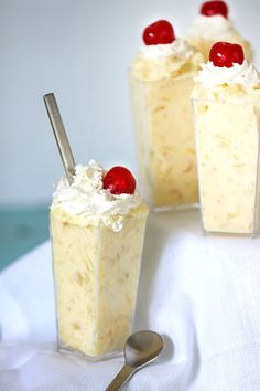 three desserts with cherries and whipped cream on top are sitting on a table