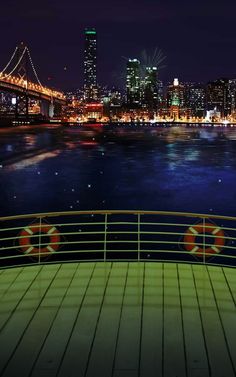 fireworks are lit up in the night sky over a river and cityscape as seen from a boat