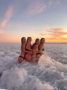 four women in bikinis riding on the back of a boat