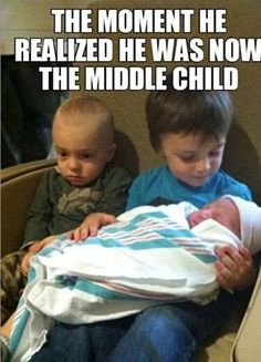 two young boys sitting next to each other holding a baby in their arms and the caption reads, the moment he revealed he was now the middle child