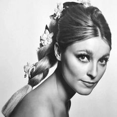 a black and white photo of a woman with flowers in her hair wearing a ponytail