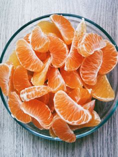 an orange is in a glass bowl on a wooden table and it appears to be peeled