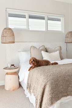 a brown dog laying on top of a bed next to two lamps and a table