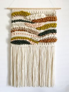 a white wall hanging with multicolored yarn