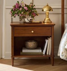 a nightstand with flowers and books on it