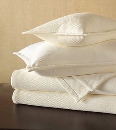 a stack of white sheets and pillows on a table