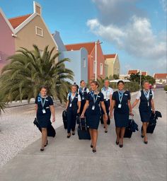 a group of women walking down a street carrying luggage