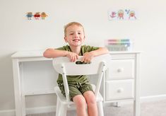 a little boy that is sitting in a chair with his legs crossed on the desk