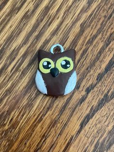 a brown and white owl with yellow eyes sitting on a wooden table next to a tag