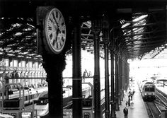 black and white photograph of train station with clock