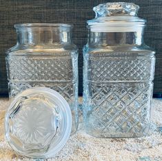 two clear glass jars sitting on top of a carpeted floor next to each other