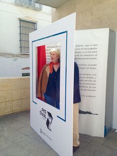 a woman standing in front of a white box with a photo on it and another person behind it