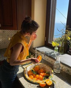 a woman standing in front of a sink filled with oranges