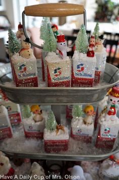 there are many small christmas decorations on the trays in the kitchen, including santa's helpers and snowmen