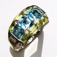 A beautifully made ring done in 18K yellow gold that has been set with 3.35cttw in blue topaz, 2.46cttw, 2.46cttw in green peridot and .09cttw in H-I color Si1-2 clarity diamonds... such a color combination! All weights are stamped inside of the shank. Dimensions/Weight: Ring measures .45" top to bottom and weighs 10.8g. Size 6 (sizable). Condition: All stones are secure and in perfectly wearable condition. R-TYE Formal Green Topaz Ring With Accent Stones, Formal Green Topaz Gemstone Ring, Anniversary Green Blue Topaz Ring, Anniversary Blue Topaz Green Ring, Gift Green Blue Topaz Ring, Green Blue Topaz Gemstone Rings, Formal Green Multi-stone Topaz Ring, Green Multi-stone Topaz Ring For Formal Occasions, Luxury Green Topaz Gemstone Ring