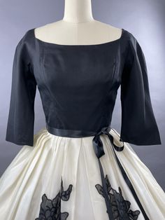 LATE 1950s SUZY PERETTE Black and White party dress with stunning black floral appliques. With a fitted bodice in a deep black taffeta she has a wide, very slightly squared neckline which is extremely flattering. Her bodice is fitted and she has elbow length sleeves. Her skirt is generous and is an organza layer over a matching lining. She features four appliques in a slightly translucent black which depict a rose and leaves. She has a plunging deep v neckline to the back and fastens with a cent Black And White Party Dress, Black And White Party Dresses, 1950s Black And White, Fashion Eras, Black And White Party, White Party Dress, Squared Neckline, White Party, Floral Applique