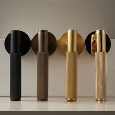 four different types of brass, black and silver items lined up against a white wall