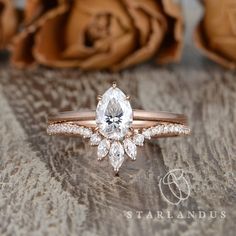 a close up of a diamond ring on a wooden surface with roses in the background