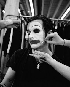 a man is getting his face painted in black and white