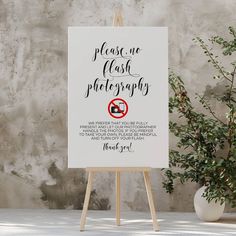 an easel with a sign that says please one flash photography on it next to a potted plant