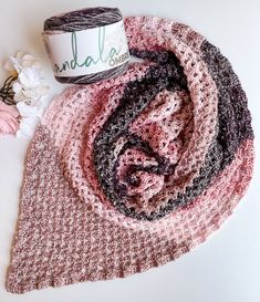 a crocheted scarf with yarn next to it on top of a white surface