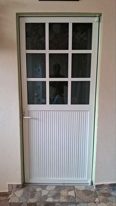 a white door with glass panes in front of a tiled floor and wall behind it