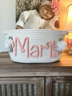 a baby is sleeping in a basket with the word mars spelled on it and flowers