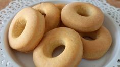 several donuts are in a white bowl on a doily